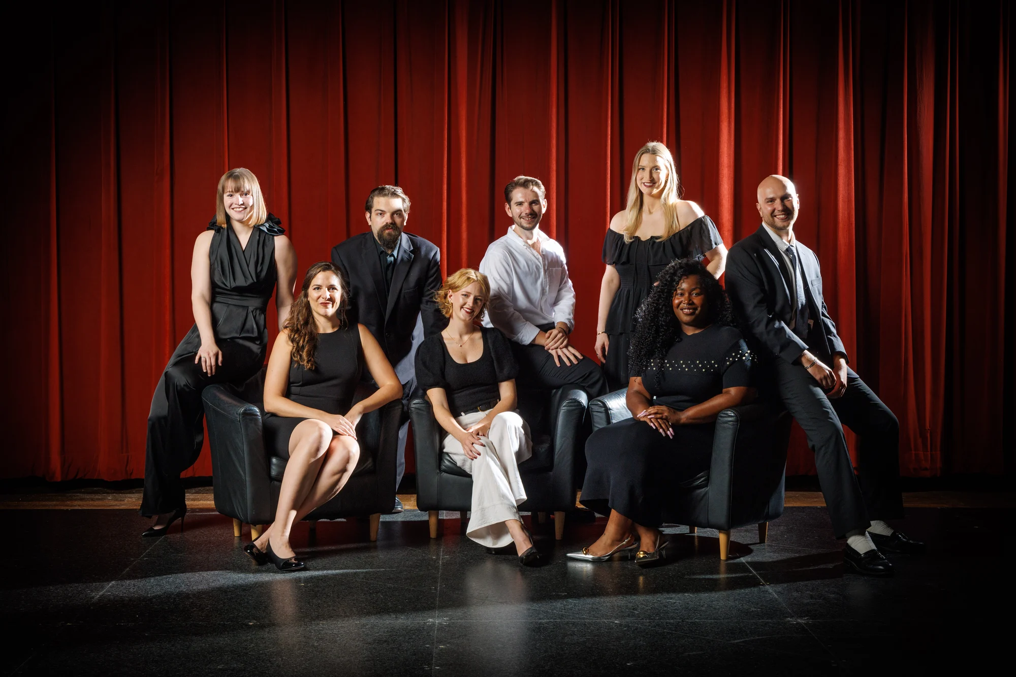 Pittsburgh Opera's 2025-26 Resident Artists, eight singers in black and white, pose before a red curtain