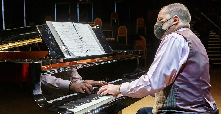 Glenn Lewis, masked, plays a grand piano from a score at the I, Too, Am America concert