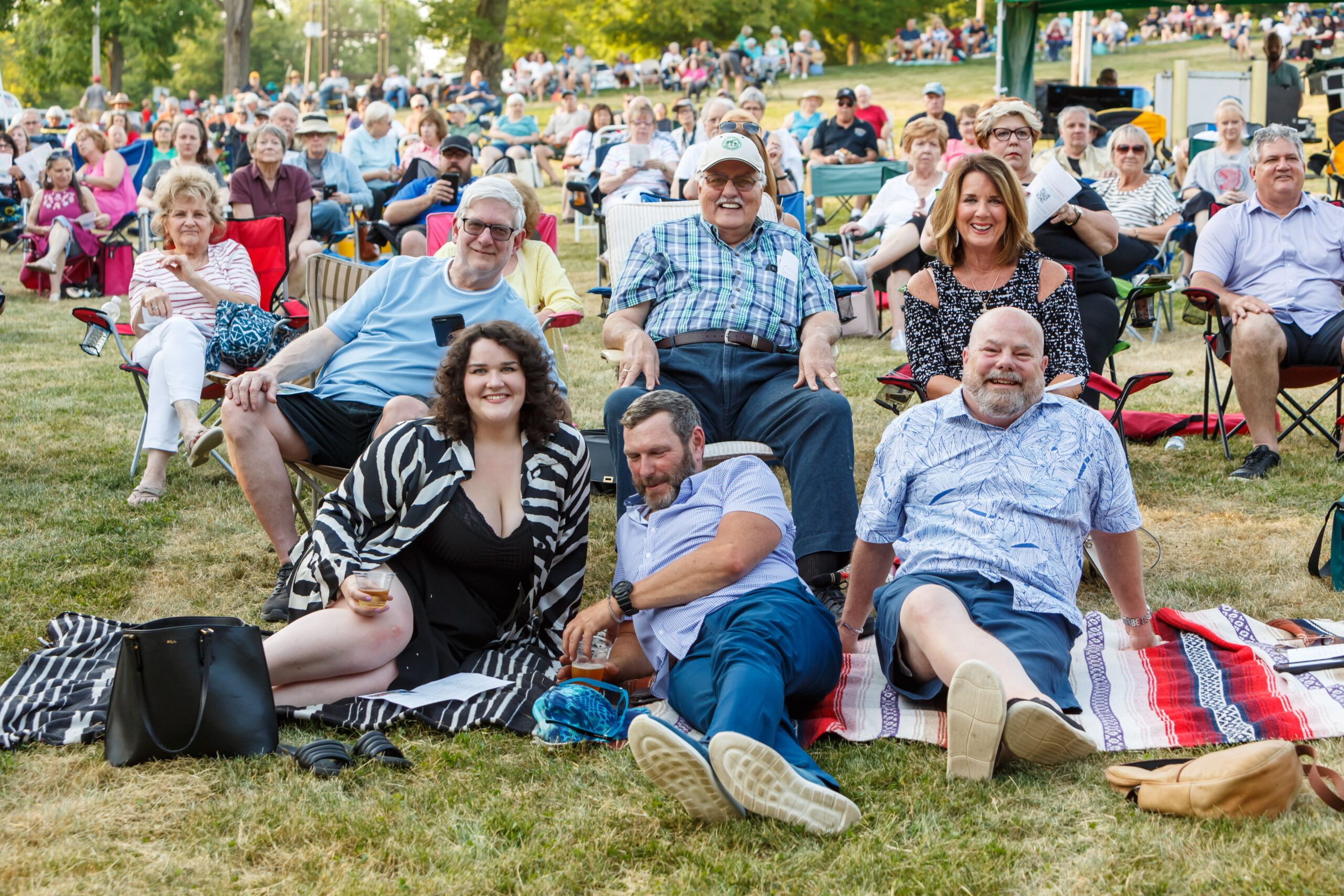 Friends relax on blankets and lawn chairs before a large crowd at a Pittsburgh Opera park concert