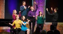 Resident Artists strike playful poses on stage as one conducts the audience at a Brown Bag concert