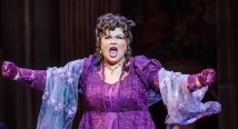 Tosca in a purple gown and curls spreads her arms singing in Pittsburgh Opera's Tosca, 2017