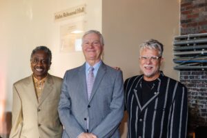 Christopher Hahn, center, with two guests beneath the new Hahn Rehearsal Hall sign at the naming ceremony