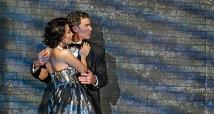 Don Giovanni in a dark suit embraces Zerlina in a sequined dress before a striped wall in Pittsburgh Opera's Don Giovanni