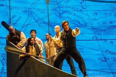 Sailors in a whaleboat point ahead against a projected sea chart in Pittsburgh Opera's Moby-Dick