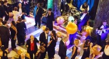 Guests dance beneath golden balloons at a New Year's Eve party, seen from above