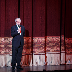 Christopher Hahn speaks into a microphone before the Benedum Center's red curtain