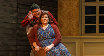 Erik in a red plaid shirt leans over Senta in a floral dress in Pittsburgh Opera's The Flying Dutchman