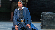Daland kneels singing in a blue coat and cap in Pittsburgh Opera's The Flying Dutchman