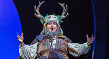 Falstaff wearing antlers and a leafy crown spreads his arms in Pittsburgh Opera's Falstaff