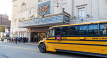 A yellow school bus pulls up under the Benedum Center marquee for a student matinee