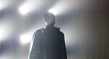 A robed figure in silhouette before a grid of glowing lights in Pittsburgh Opera's In a Grove