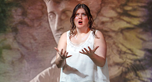 Emily Richter in white sings before a projected carved face in Pittsburgh Opera's Iphigenie en Tauride