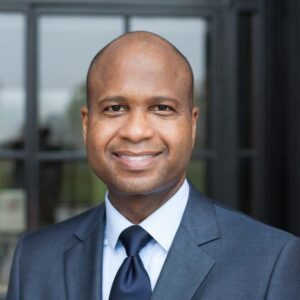Michael Edward Braxton in a grey suit and navy tie, portrait
