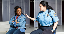Kirstin Chavez as Glenda, a police officer, comforts a young woman in denim in Pittsburgh Opera's We Shall Not Be Moved