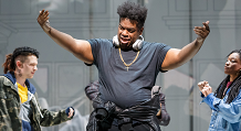 A singer in a black hoodie with headphones spreads his arms in Pittsburgh Opera's We Shall Not Be Moved