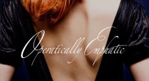 Operatically Emphatic in white script over a red-haired woman's bare back in a black dress