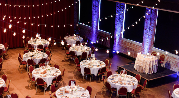 The Bitz Opera Factory set with round tables, red chairs, and string lights for an event