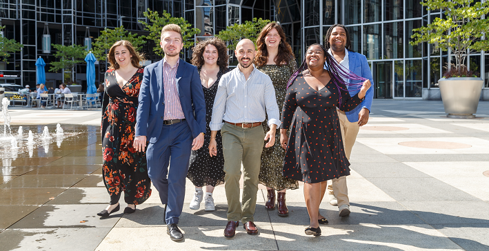 The 2023-24 Pittsburgh Opera Resident Artists walk together across a sunny Downtown Pittsburgh plaza