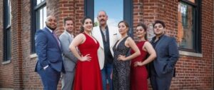 The seven 2019-20 Pittsburgh Opera Resident Artists pose in formal wear outside a brick building