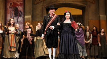 Escamillo in a plaid sash and Carmen in black lace lead a crowd of villagers in Pittsburgh Opera's Carmen