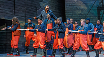 Fishermen in orange waders haul a rope across the stage in Pittsburgh Opera's The Flying Dutchman
