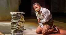 Charlie Parker, masked, kneels beside a stack of sheet music in Pittsburgh Opera's Charlie Parker's Yardbird