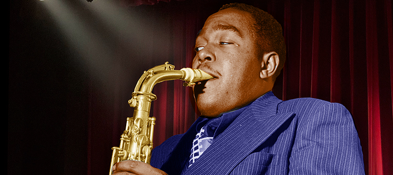 Charlie Parker plays alto saxophone in a blue pinstripe suit before red curtains; Charlie Parker's Yardbird key art