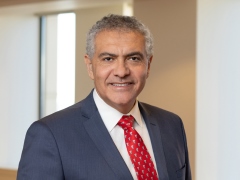 Tarek Abdalla in a navy suit and red tie, portrait