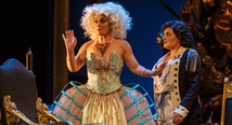 Alcina in a towering white wig raises her arms before a gilded backdrop in Pittsburgh Opera's Alcina
