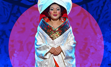 Cio-Cio San in a white wedding kimono and hood before a red circle on blue; Madama Butterfly 2025 key art