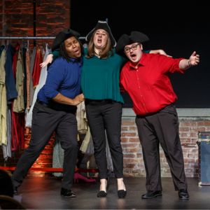 Three Resident Artists in pirate hats sing arm in arm before a costume rack at a Song Shop concert
