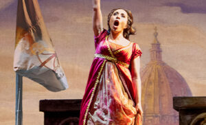 Tosca in a red gown raises her fist before a flag and a Roman dome; Pittsburgh Opera Tosca 2024 key art