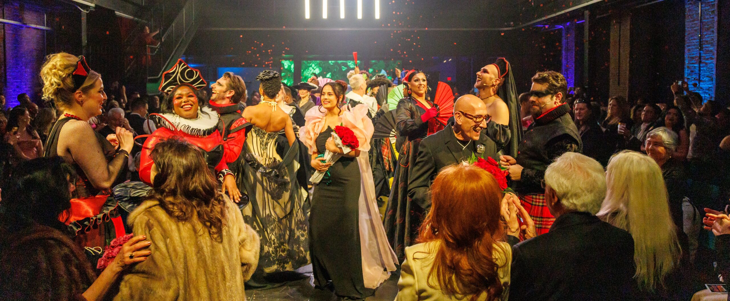 Models in opera-inspired costumes crowd the runway as guests applaud at the Pittsburgh Opera Fashion Show finale